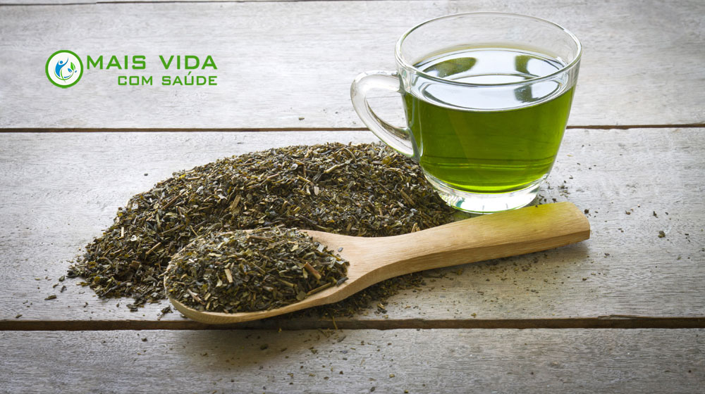 Xícara de chá verde recém-preparado com folhas naturais